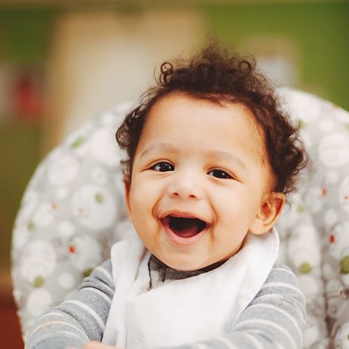 smiling baby with dark curly hair